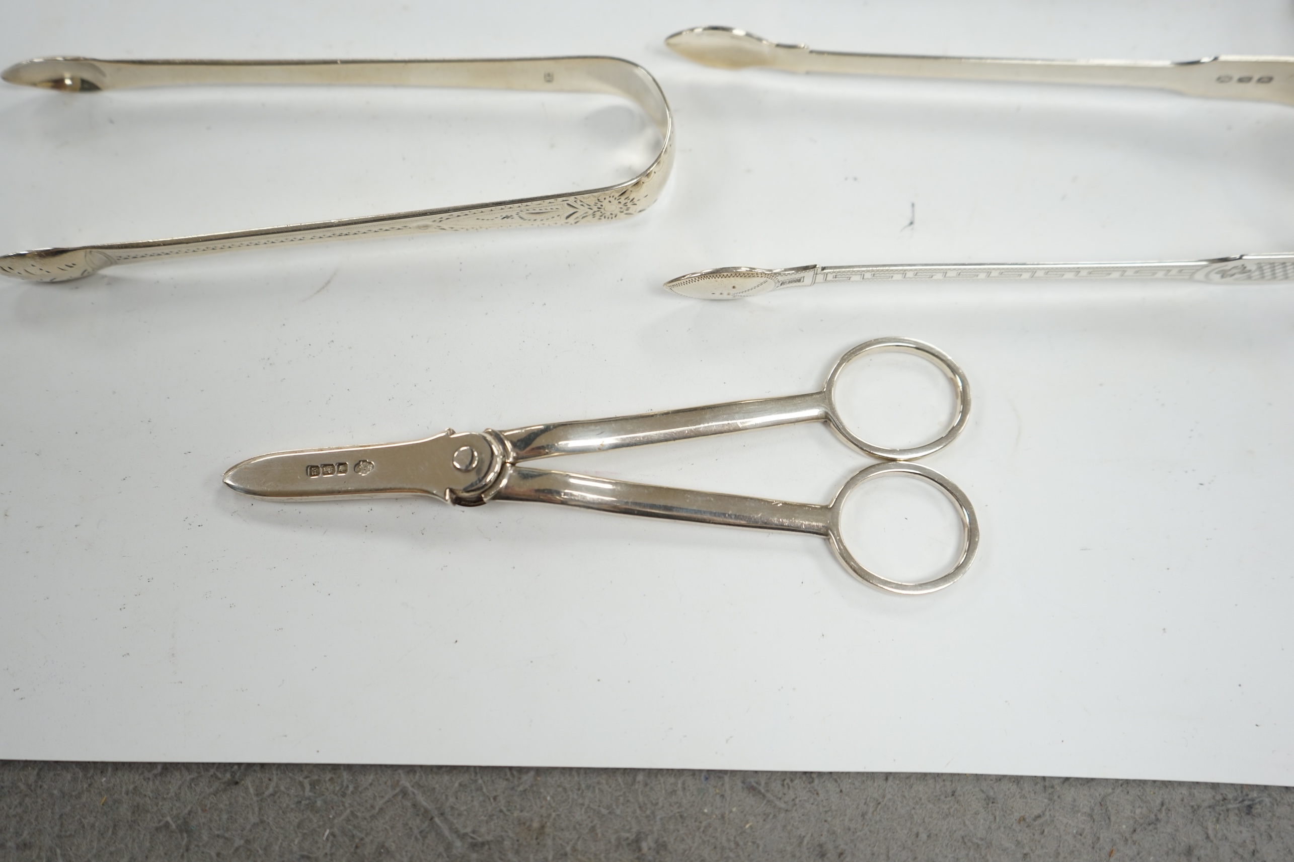 A pair of George V silver grape scissors, by William Hutton & Sons, two pairs of silver sugar tongs and a Georgian silver punch ladle. Condition - poor to fair